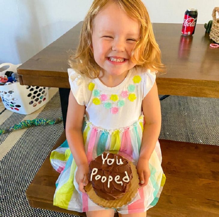 Clever and funny dads that win at parenting, Little girl holding cake that says “You pooped”