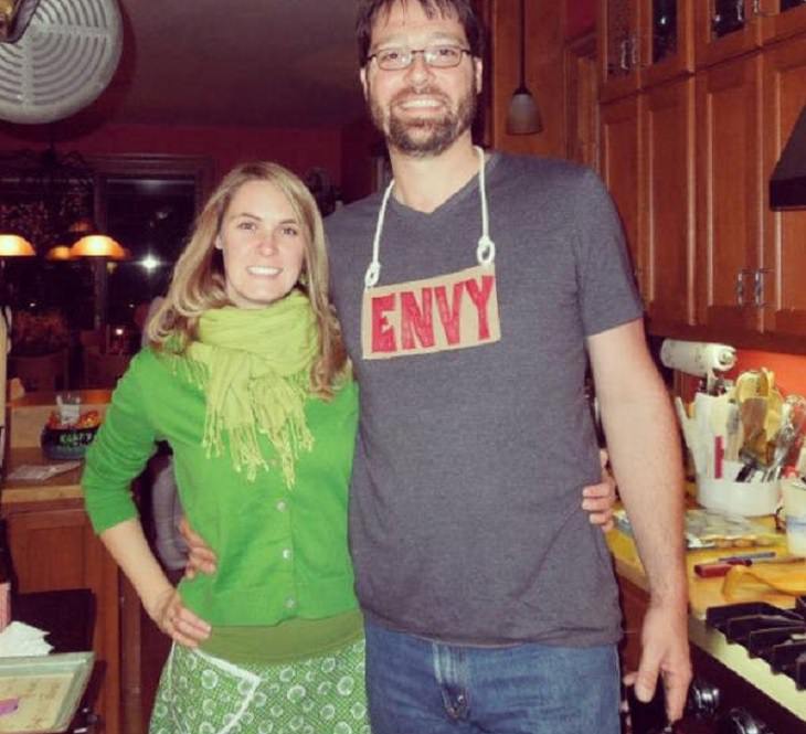 Hilarious and clever Halloween costumes based on puns and word play, Woman in green next to man with sign saying “Envy”