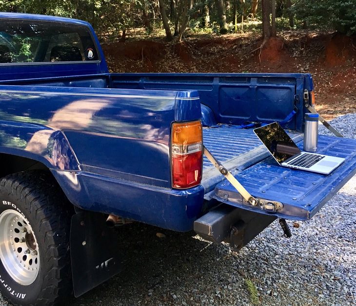 Funny improvised and makeshift work from home (wfh) workspaces and workstations, using the back of a pickup truck as a laptop desk