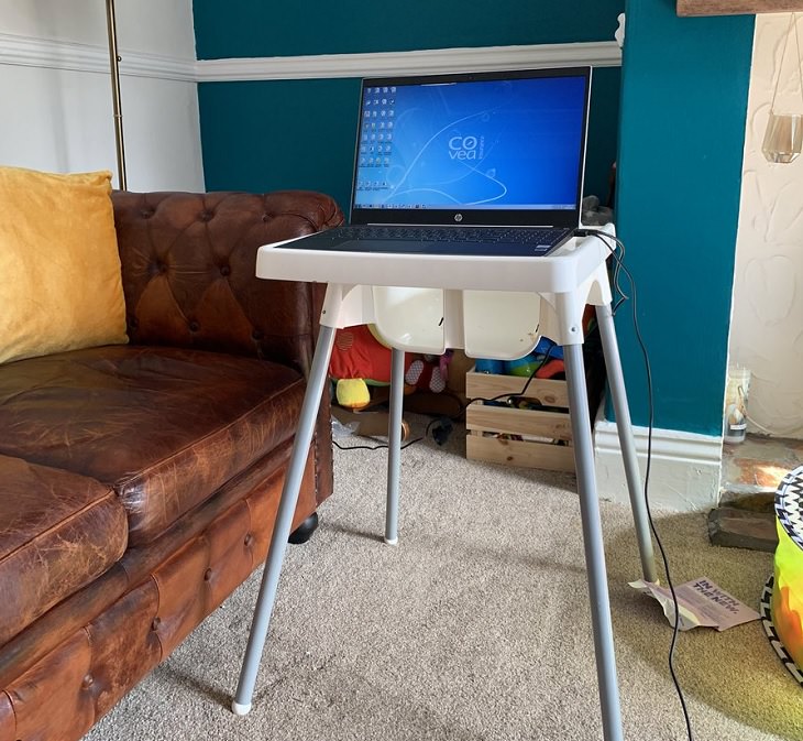 Funny improvised and makeshift work from home (wfh) workspaces and workstations, using baby high chair as a laptop desk