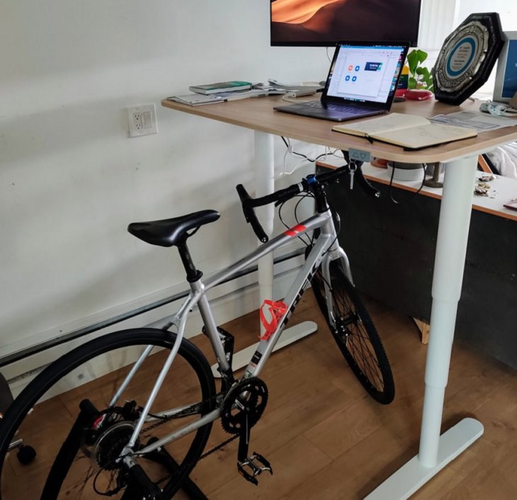Funny improvised and makeshift work from home (wfh) workspaces and workstations, work desk fitted with a bicycle