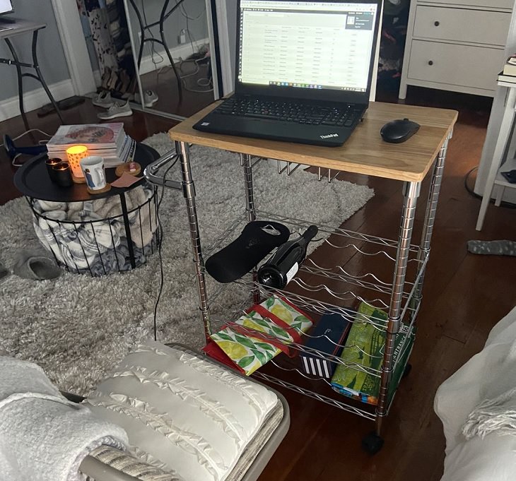 Funny improvised and makeshift work from home (wfh) workspaces and workstations, using moveable cabinet with wine bottle as a laptop desk