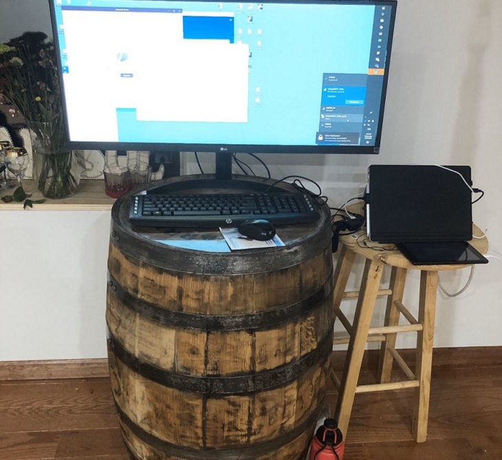 Funny improvised and makeshift work from home (wfh) workspaces and workstations, barrel used for keyboard and stool used for laptop in stand workstation