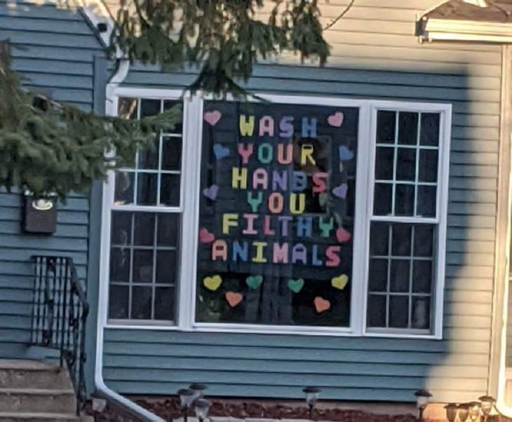 Funny signs related to the quarantine and lockdown caused by the COVID-19 (coronavirus) pandemic, multicolored sign made on window saying “Wash your hands, you filthy animal.”