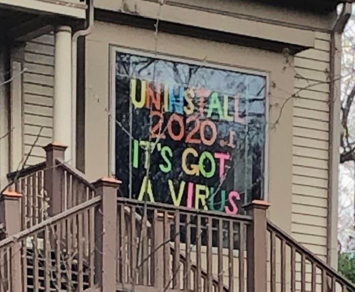 Funny signs related to the quarantine and lockdown caused by the COVID-19 (coronavirus) pandemic, multicolored sign stuck to window saying “Uninstall 2020. It has a virus.”