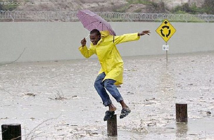 Hilarious photos showing things that can happen only in Africa, Man with umbrella jumping from wooden posts in a flood