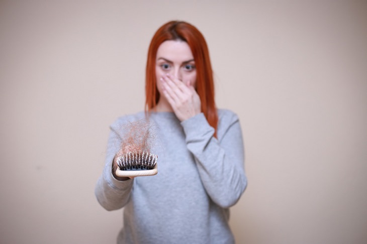 Household items that should not have the vacuum cleaner used on them, Woman holding brush covered in hair