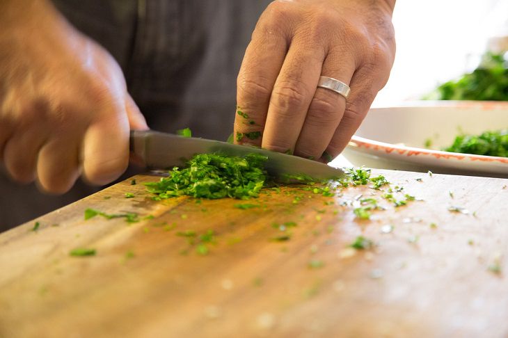Food safety facts and myths you need to know about, Man chopping green leafy vegetable on a chopping board