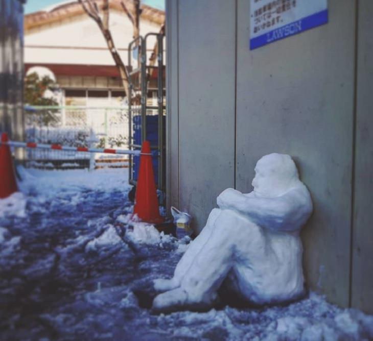 Residents of Tokyo create creative and unique snowmen and ice sculptures, Snow sculpture of man sitting and leaning against a wall