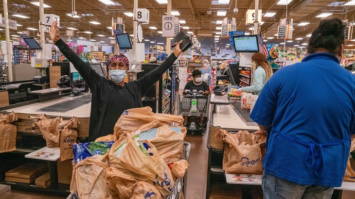 Best feel good stories of 2020, Woman with arms outstretched in joy at a grocery store