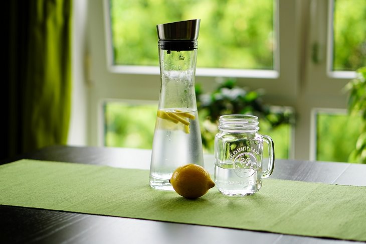 Drinks healthy to have while fasting, Bottle of water, mug of water, and lemon on a table