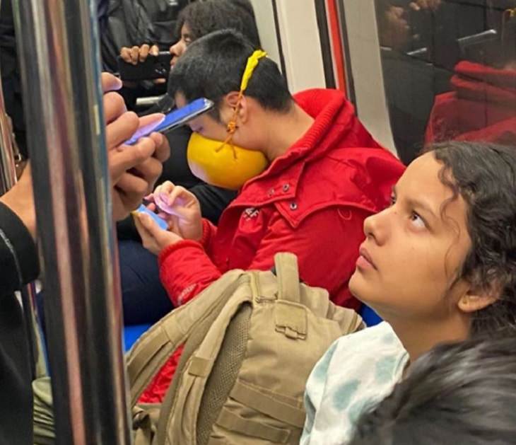Hilarious photos of strange masks spotted on the subway, Man sitting using his phone with a yellow bowl tied to his face