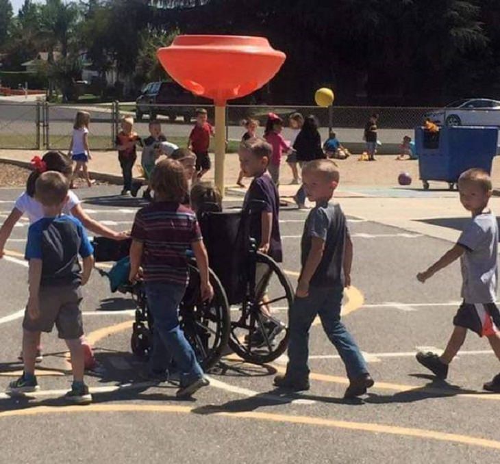 Photos of feel good stories that will make you smile, Little girl in a wheelchair surround by other kids