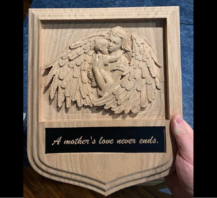 Wood masterpieces made by amateurs and experts, Wooden plaque with a carving of angel holding baby with the line “a mother’s love never ends”