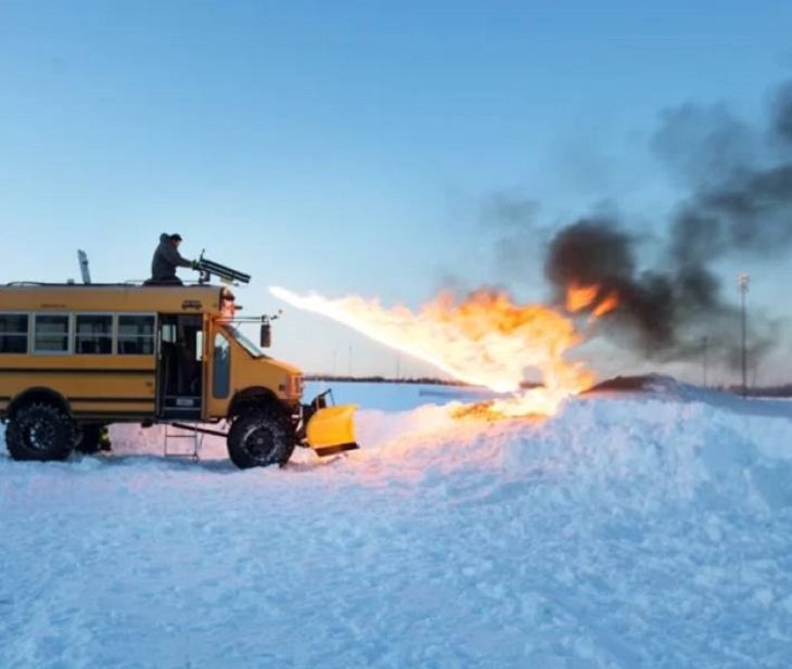 Makeshift, unique, and creative snowplows, yellow bus with man holding flamethrower lighting hill of snow on fire