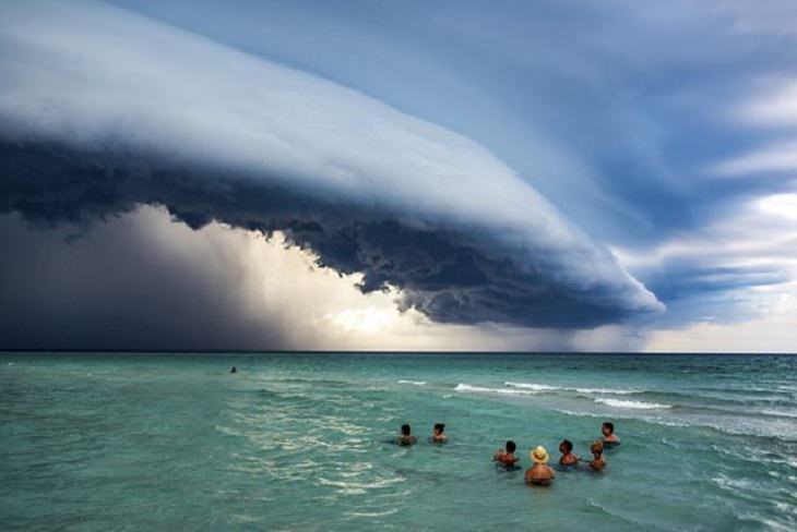 Winners of the Nature Conservancy World wide Photo Competition / Contest, People in Nature, Honorable Mention: Giovani Cordioli, Brazil CUBAN STORM: Swimmers look to the sky as a storm comes over Varadero, Cuba in 2019