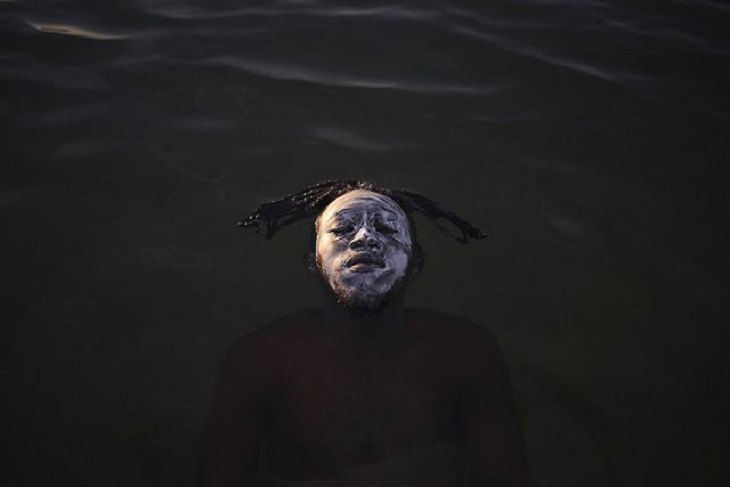 Winners of the Nature Conservancy World wide Photo Competition / Contest, People in Nature, Second Place: Fabio Teixeira, Brazil PORTRAIT IN GUANABARA BAY: A young refugee from the Democratic Republic of Congo floats in Guanabara Bay, Ramos Beach in Rio De Janeiro