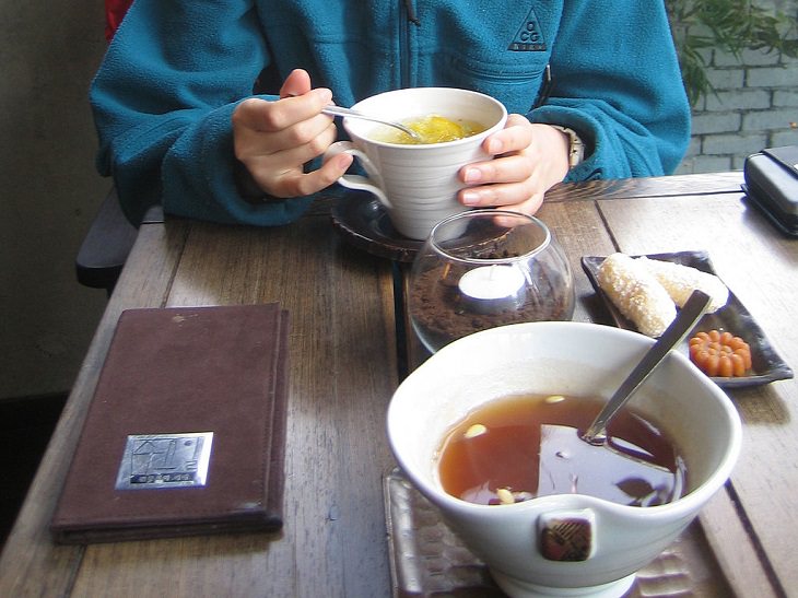 Recipe for healthy Korean traditional cold fruit tea, good for digestion, Sujeonggwa, person eating dinner with bowl of tea on table