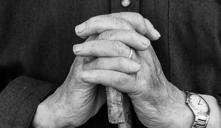 old hands holding a walking stick