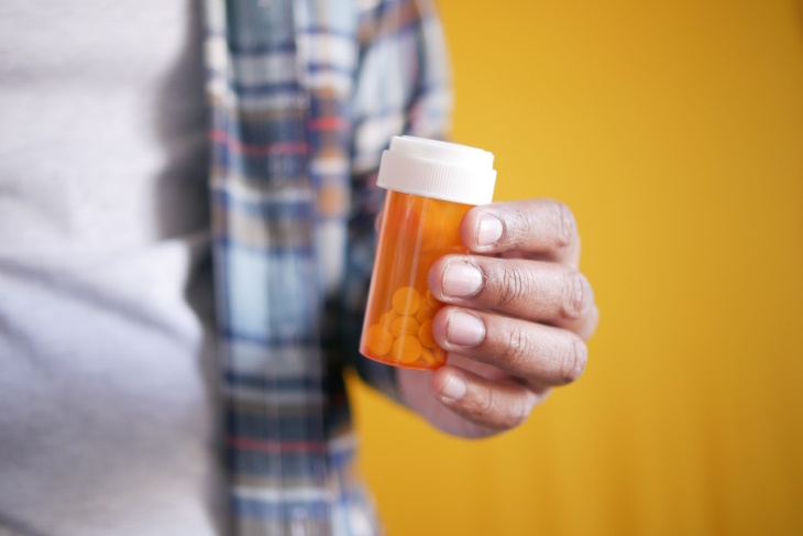 Alpelisib for anti-aging man holding a bottle with pills