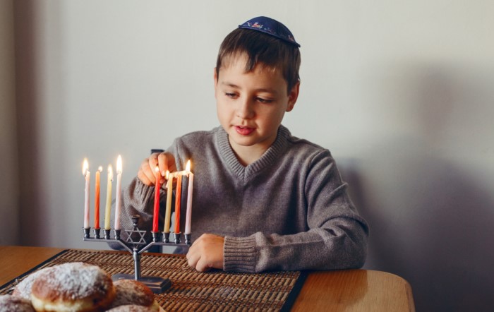 Jewish boy lighting up menorah