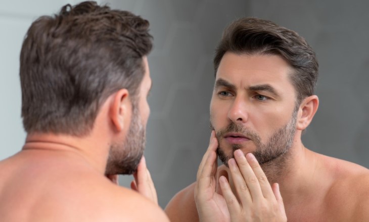 man checking his skin in the mirror