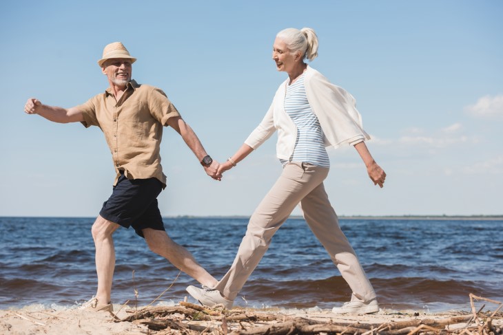 homem e mulher idosa passeando na praia