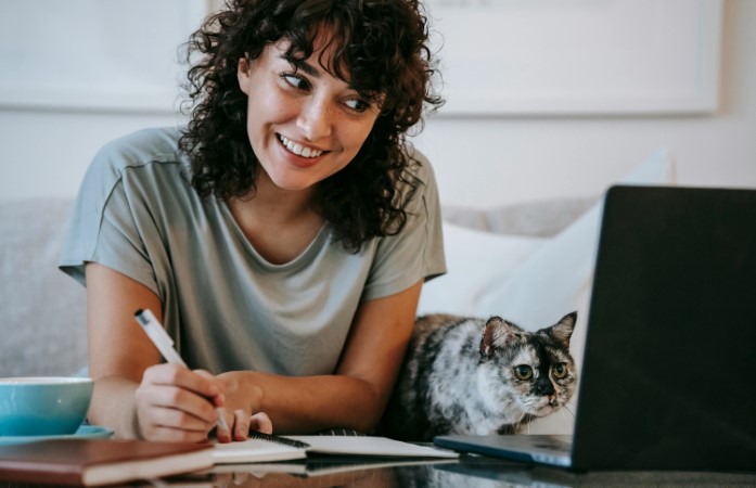 girl writing in front of laptop and smiling