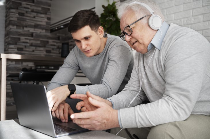 senior watching laptop with younger man