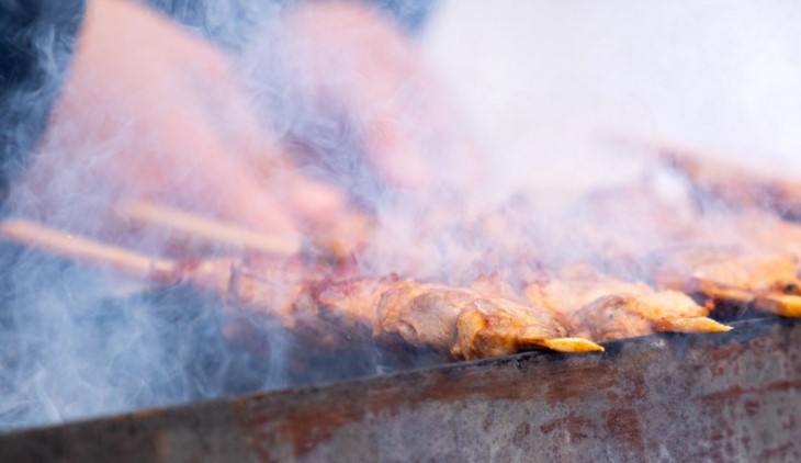 grilling skewers of meat with smoke