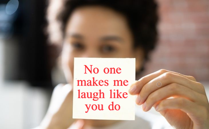 How to compliment your partner: A woman holding a note that says 'No one makes me laugh like you do'