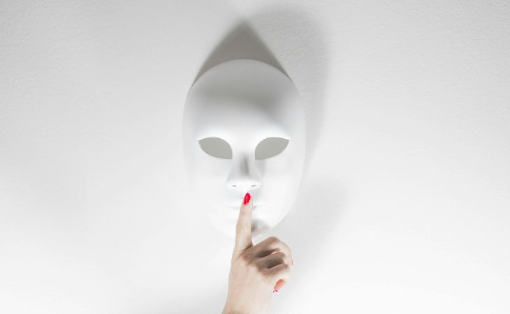 Phrases narcissists say to make you feel bad: a mask with a finger on the lips