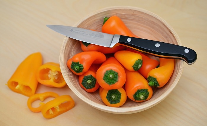 Household Injuries: sharp knife on a bowl of orange peppers