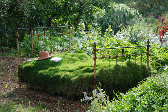 Recycled Furniture 4 post bed used to grow plants on as part of garden  with a hat and a book on it