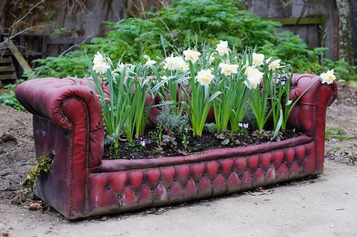 Recycled Furniture growing flowers out of a red sofa in the garden