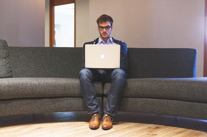 Back pain young man with laptop sitting on sofa