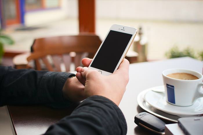 Benefits of Using Google Drive: holding a smartphone at a cafe 