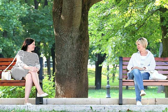 Two women sitting on benches in the park