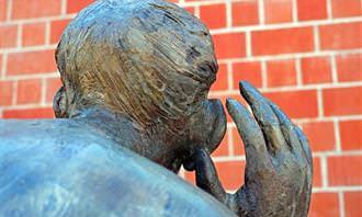 A sculpture of a figure turning an ear to listening