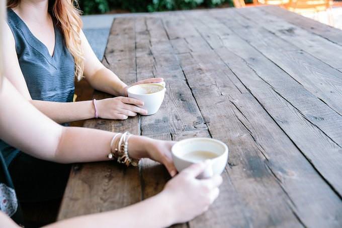 the hands of two women having coffee together