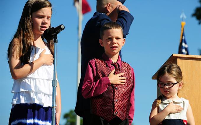Children wit their hands on their hearts singing the anthem
