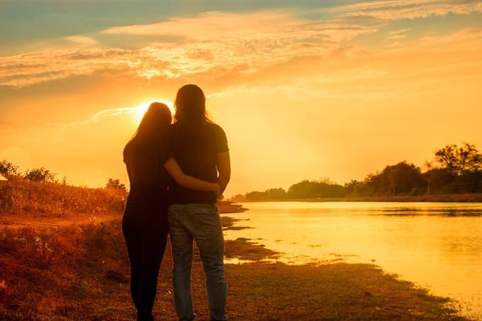 A man and woman hugging in front of the sunset