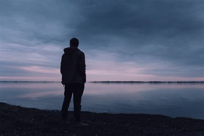 The silhouette of a man standing in front of the sea early in the morning