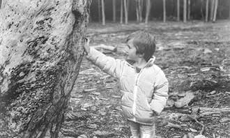 Kid leaning on tree