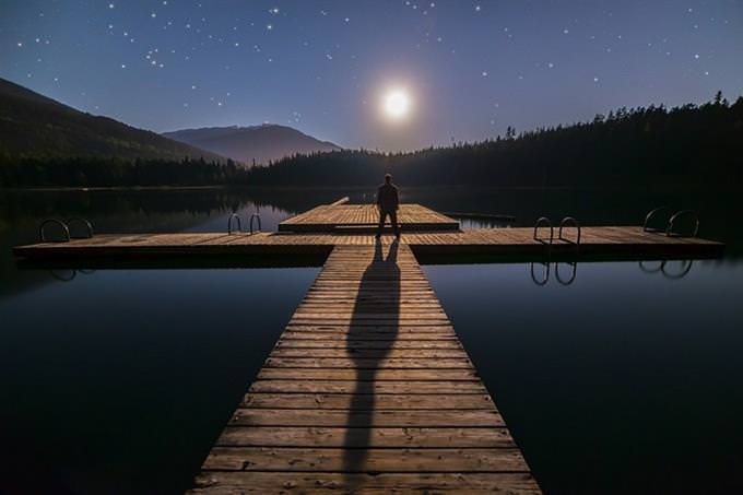 Man on a dock looking at moon