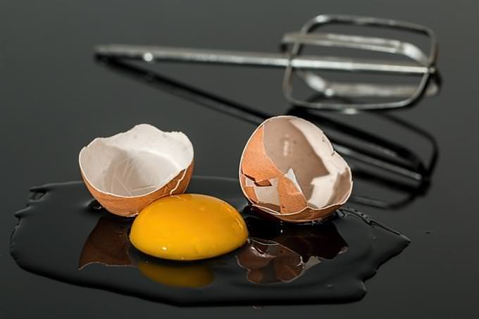 A broken egg next to a mixer