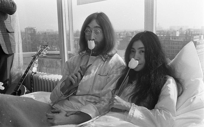 John Lennon and Yoko Ono sit with flowers