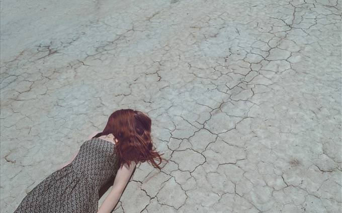 woman lying on cracked earth