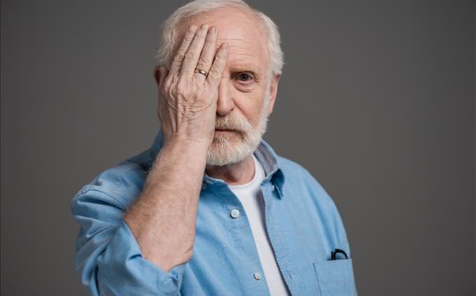 elderly man with hand over eye