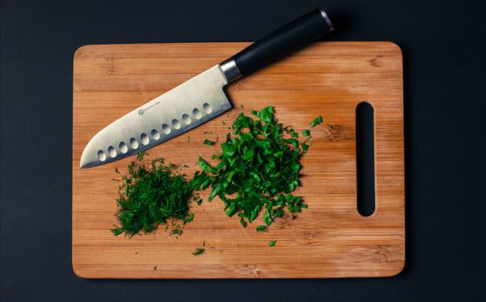 knife and herbs on wooden chopping board
